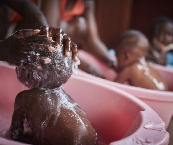 Young children are bathed by their mothers.