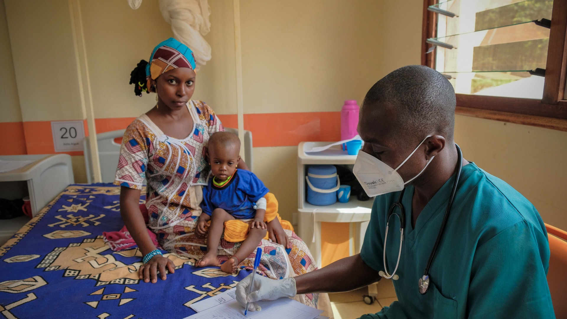 A healthcare worker in a mask with a mother and child at the pediatric hospital in Bangui, Central African Republic.